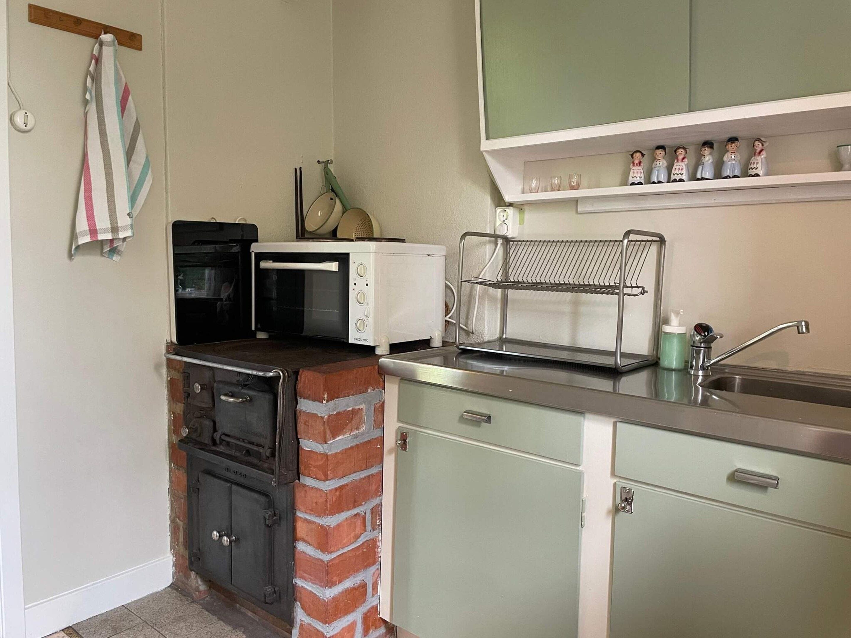 A compact kitchen with a microwave, toaster, and a brick oven.