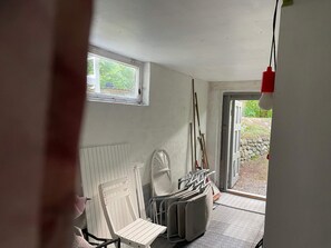 A room with a radiator, a white chair, a table, and a door leading outside.