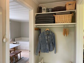 Una habitación con cama, mesa de comedor y armario con ropa doblada y perchas.