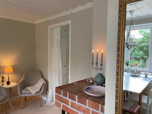 A room with a brick fireplace, a table with candles, a chair, and a lamp. - 4 Person Holiday Home in 38472 (Timmernabben)
