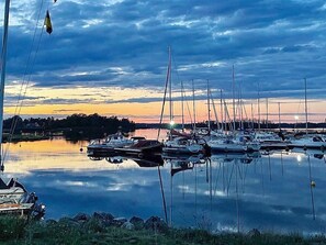 A marina with multiple boats docked, calm water, and a sunset in the background. - 4 Person Holiday Home in 38472 (Timmernabben)
