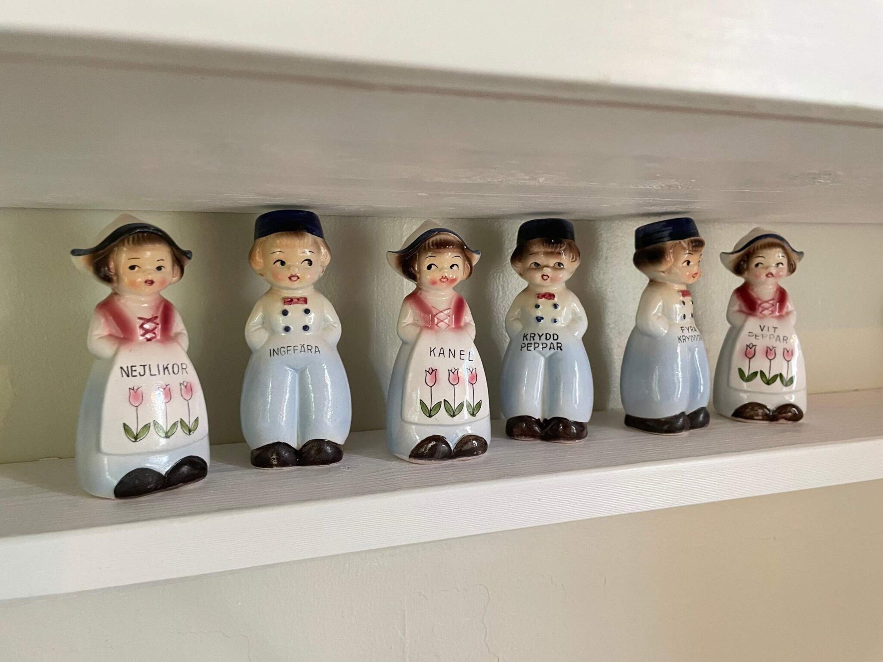 En hylla med keramikfigurer föreställande kvinnor i traditionella dräkter.