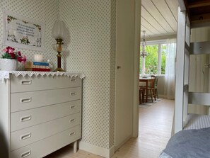 A room with a dresser, a framed picture, a vase with flowers, and a window with a view of greenery. - 4 Person Holiday Home in 38472 (Timmernabben)
