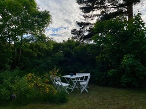 An outdoor seating area with a table and chairs, surrounded by dense foliage and trees. - 4 Person Holiday Home in 38472 (Timmernabben)