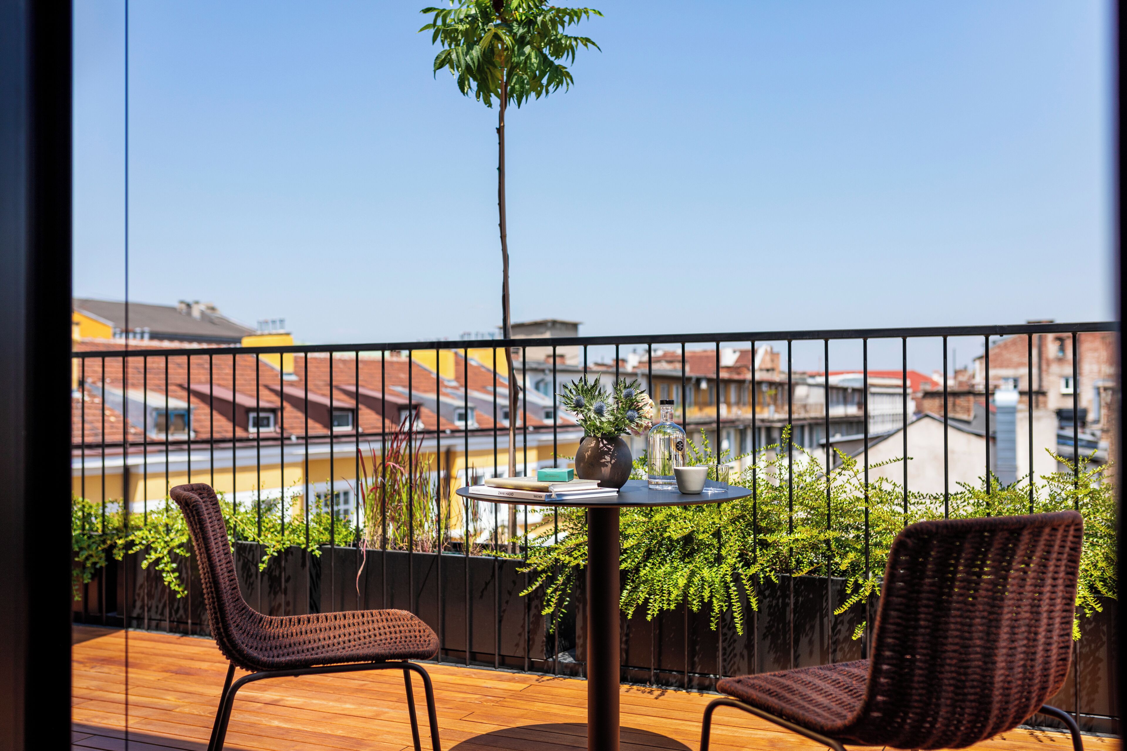 A balcony with wicker chairs, a small round table, and a potted plant.