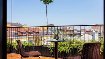 Un balcon avec des fauteuils en osier, une petite table ronde et une plante en pot.