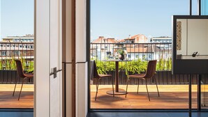 A modern hotel room with a large window, a balcony with chairs, and a bed. - Juno Hotel Sofia, a Member of Design Hotels (Sofia)
