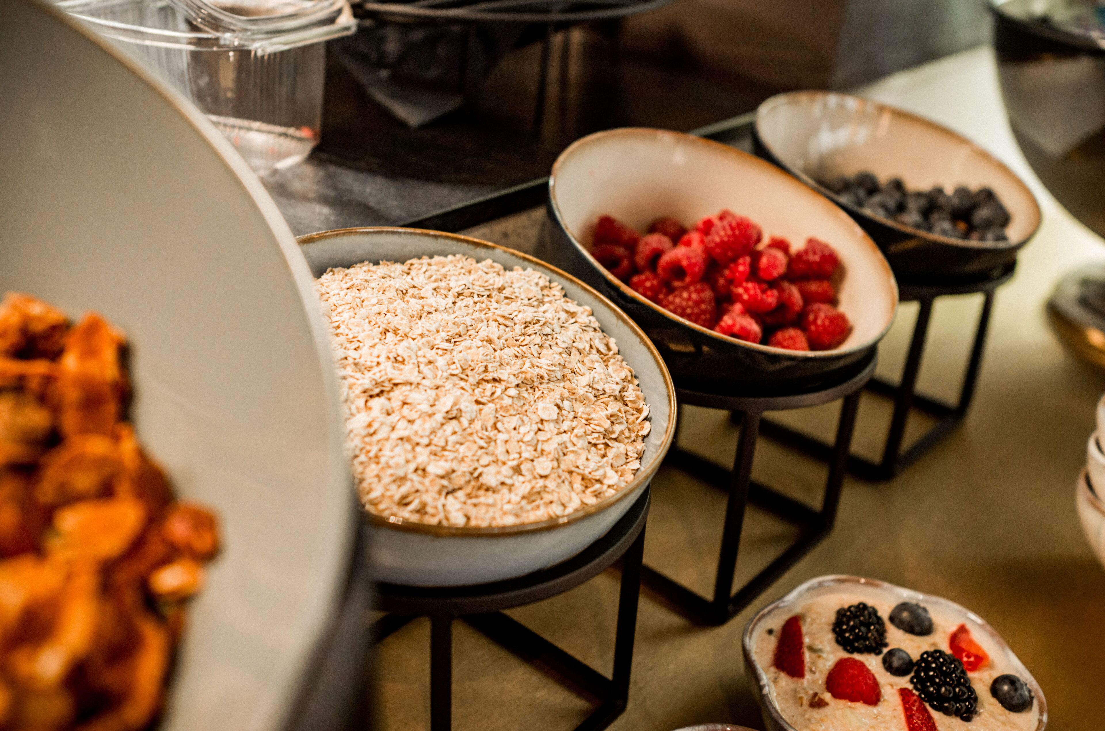 A buffet with various food options including oats, raspberries, and a dessert with berries.
