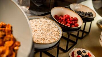 A buffet with various food options including oats, raspberries, and a dessert with berries.