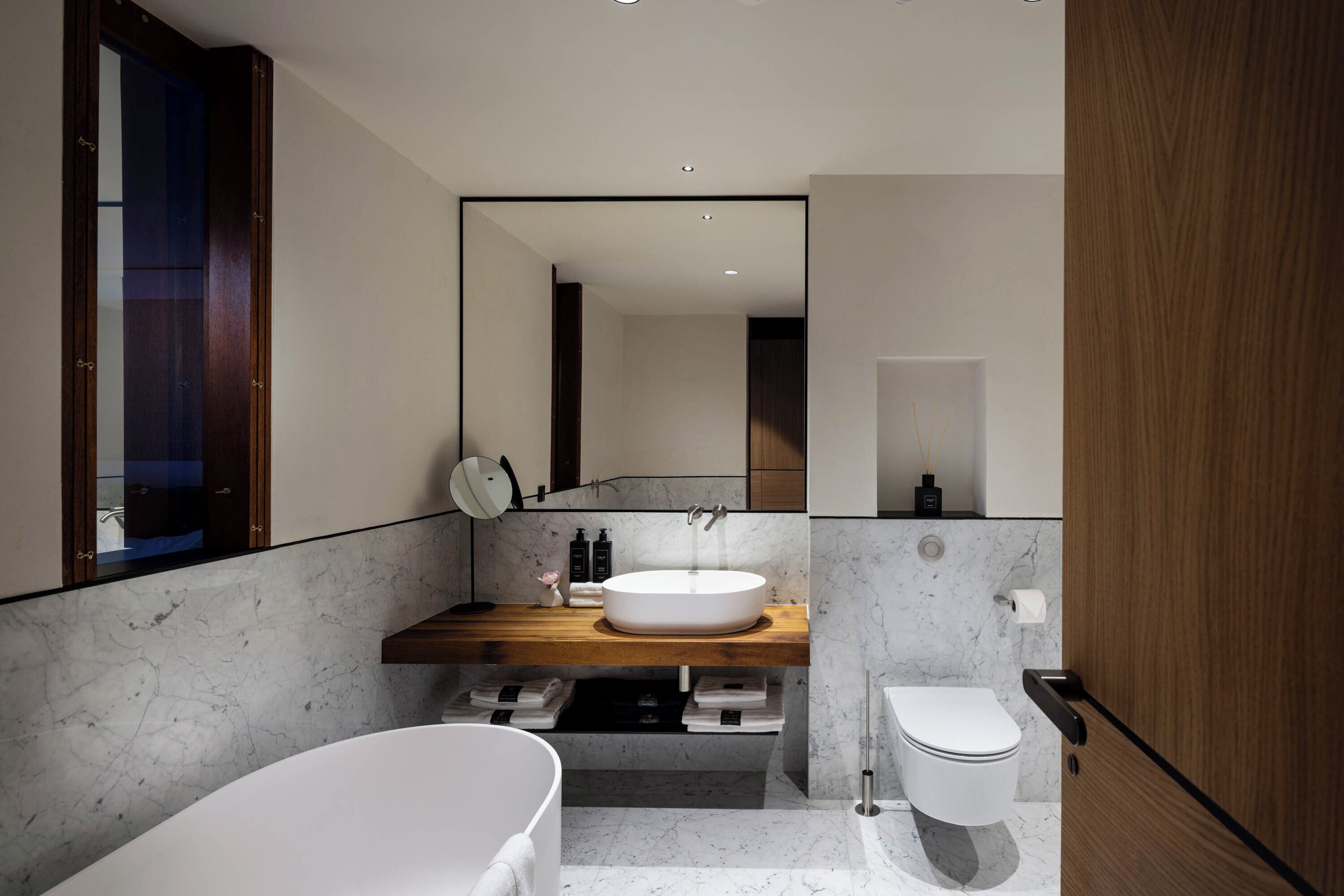 A modern bathroom with a freestanding bathtub, a round sink, and a toilet.