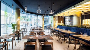 A restaurant with tables set for dining, a bar area, and large windows offering a view of the street. - Juno Hotel Sofia, a Member of Design Hotels (Sofia)