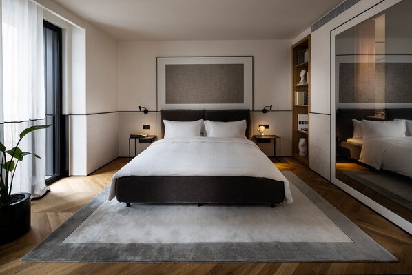 A modern bedroom with a large bed, bedside tables, a nightstand, a potted plant, and a large mirror. - Juno Hotel Sofia, a Member of Design Hotels (Sofia)
