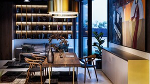 A modern interior with a wooden dining table, chairs, a bookshelf, and a large painting. - Juno Hotel Sofia, a Member of Design Hotels (Sofia)