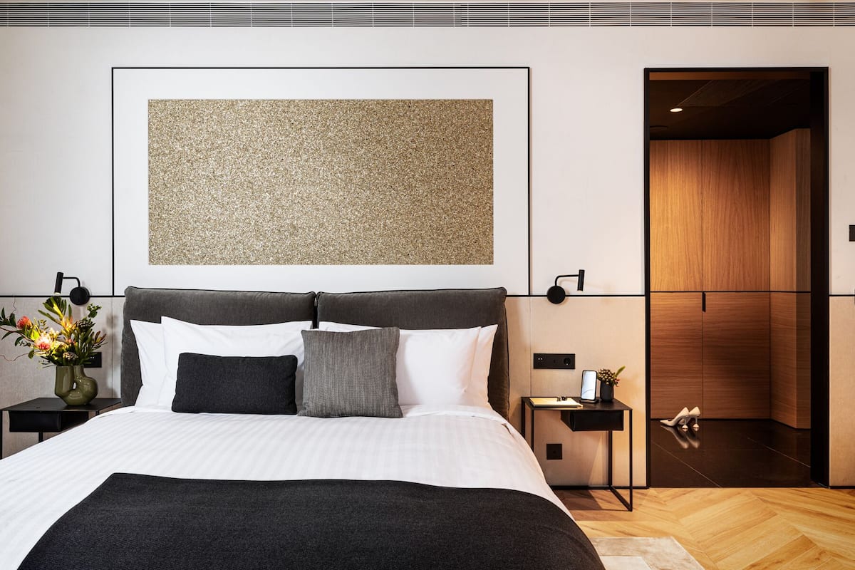 Quarto moderno com uma cama grande, uma porta de madeira e uma obra de arte na parede.