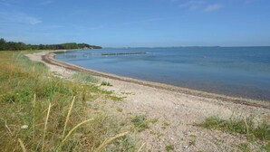 A coastal beach with a clear sky, a sandy shore, and a calm sea. - 5 Person Holiday Home in Thyholm (Thyholm)