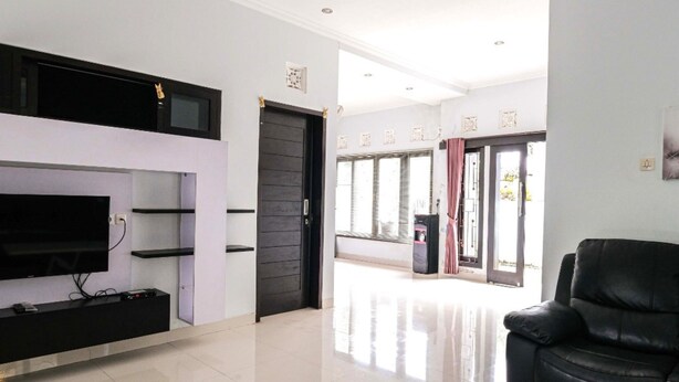 Een moderne woonkamer met een flatscreen televisie, een zwarte leren bank en een minimalistisch design.