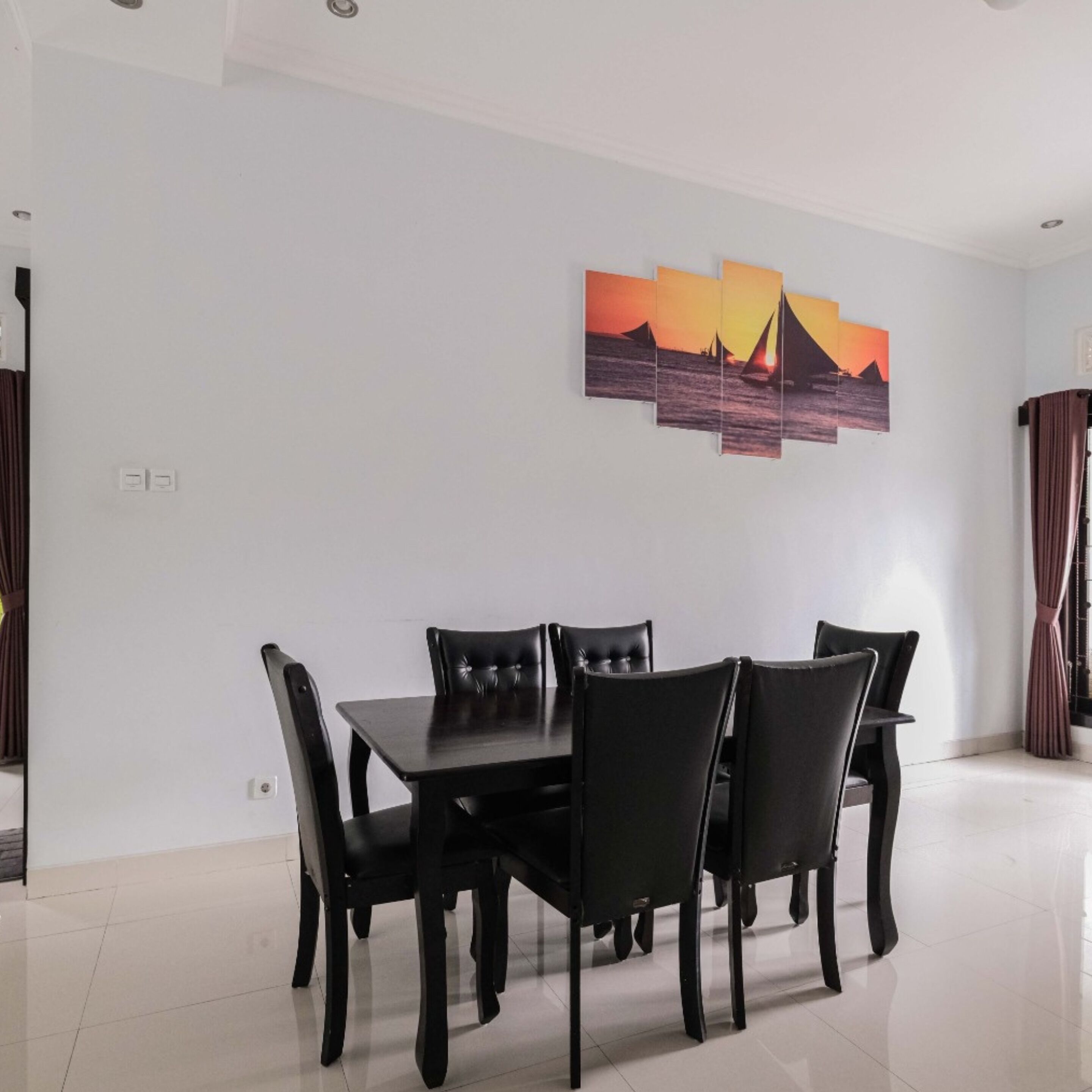 Un comedor con una mesa y sillas, un cuadro en la pared y una cortina.