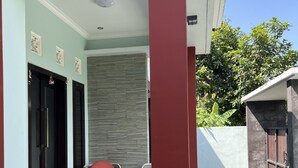 Een modern huis met een overdekte veranda, een rode kolom en een stenen muur.