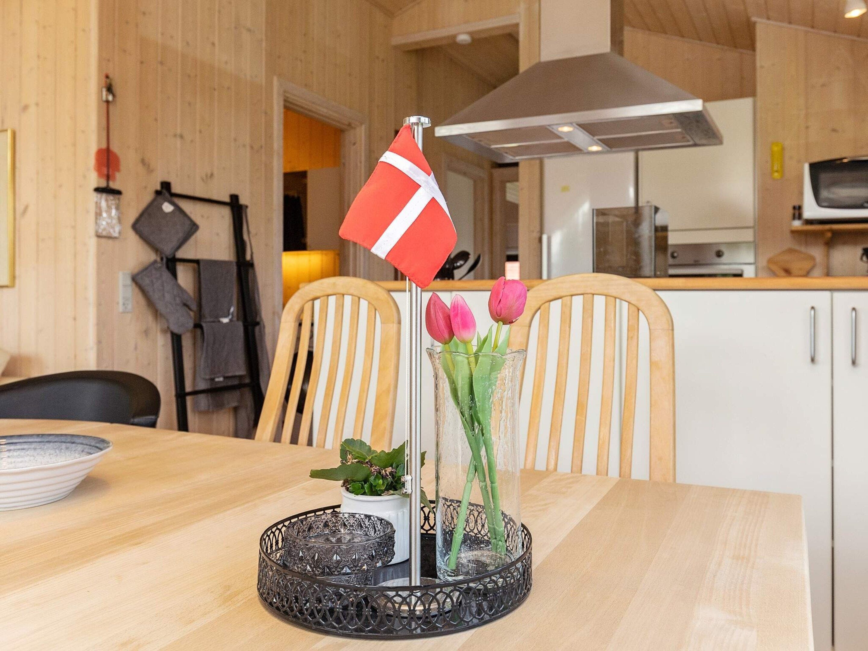 Ruokapöytä, jonka päällä on lippu, maljakko kukkineen ja koristeellinen tarjotinalusta.