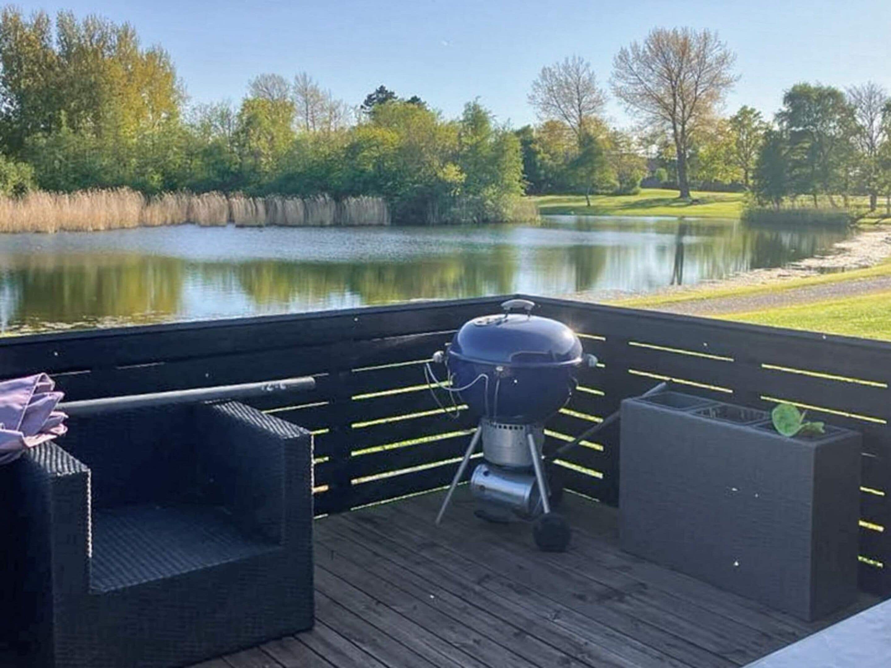 A deck with a grill, a chair, and a planter.