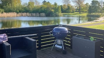 A deck with a grill, a chair, and a planter.
