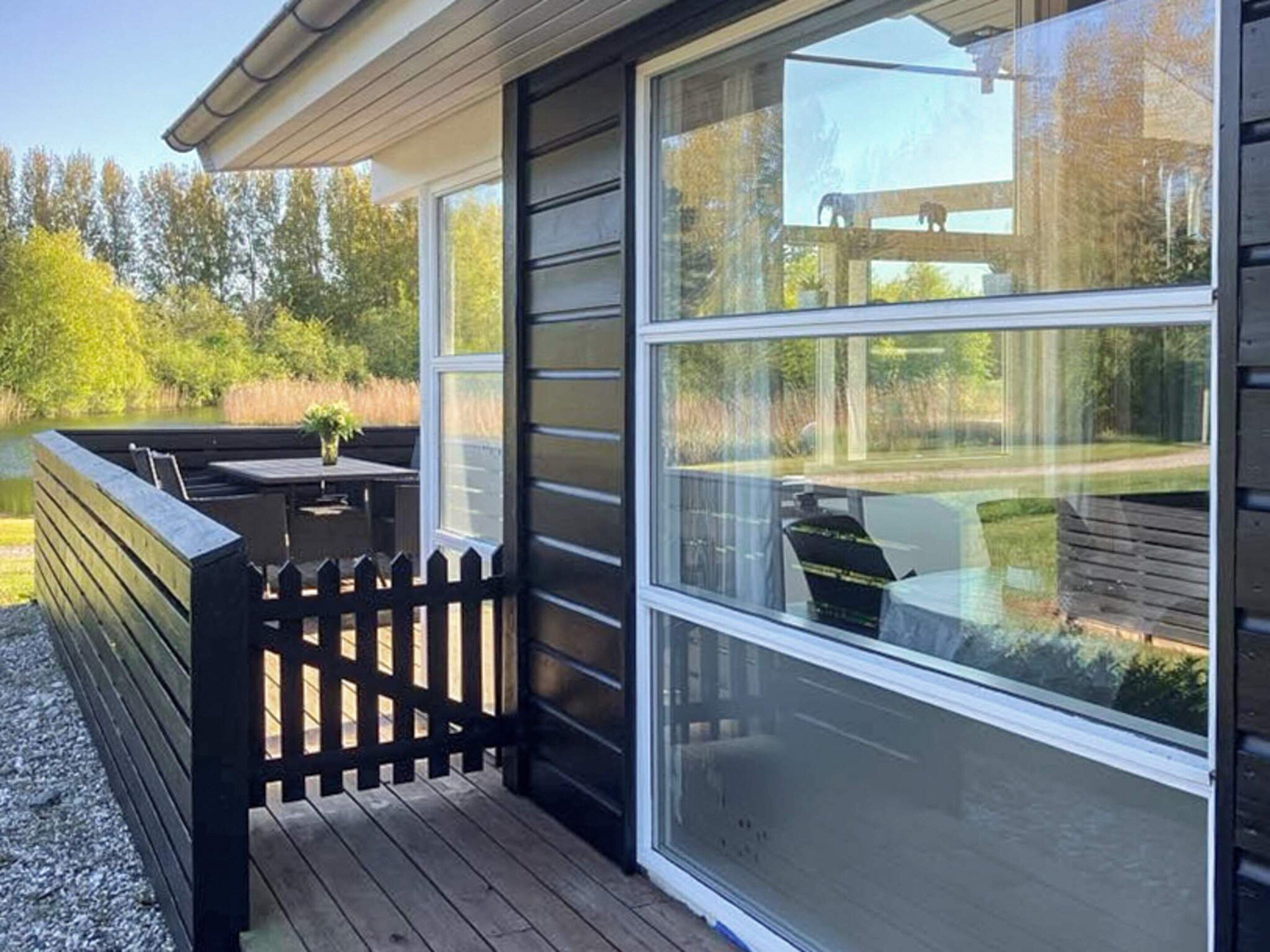 Eine Terrasse mit Holzzaun, Tisch und Stühlen mit Blick auf eine natürliche Landschaft.