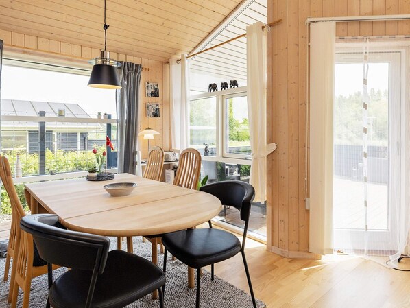 A dining area with a wooden table, black chairs, and a hanging light fixture.