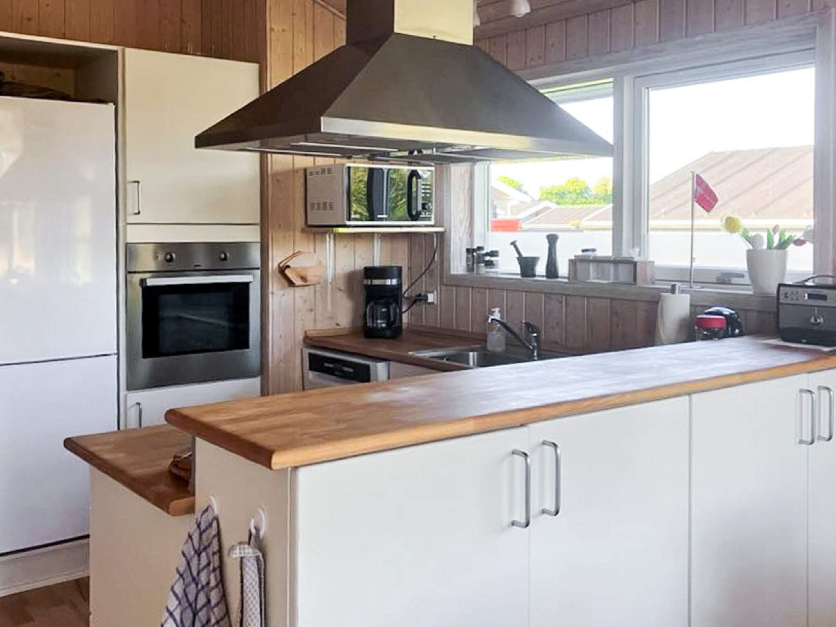 Een moderne keuken met witte kasten, roestvrijstalen apparatuur en een houten aanrecht.