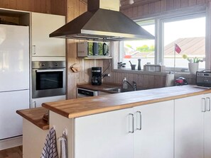 A modern kitchen with white cabinets, stainless steel appliances, and a wooden countertop.