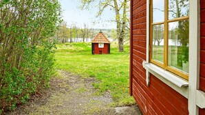 A red wooden building with a window and a small red structure in the background. - 3 Person Holiday Home in Flen (Flen)