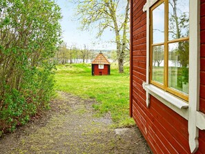A red wooden building with a window and a small red structure in the background.