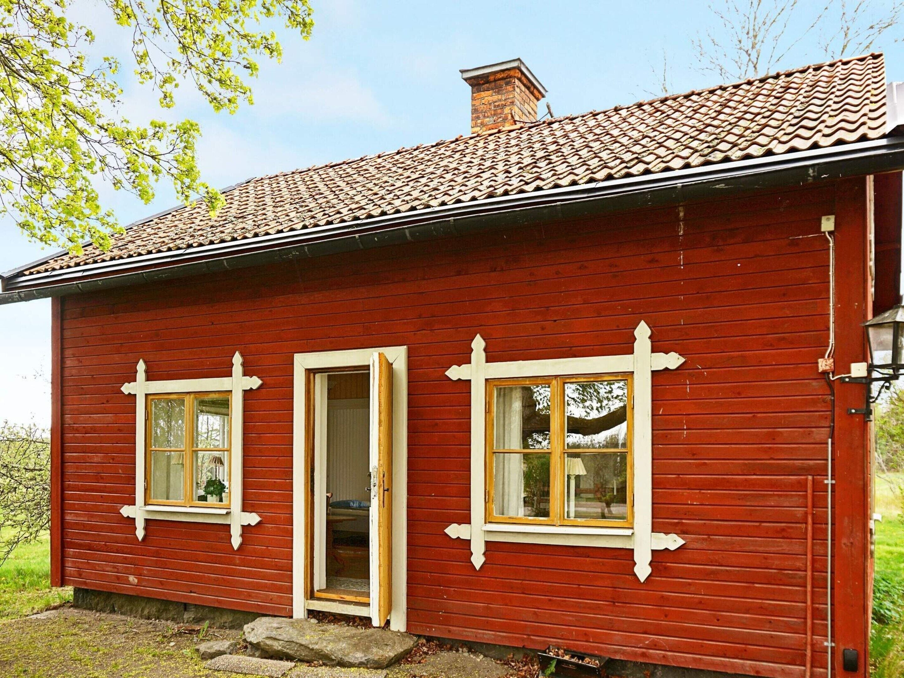 A red wooden house with three windows and a door.