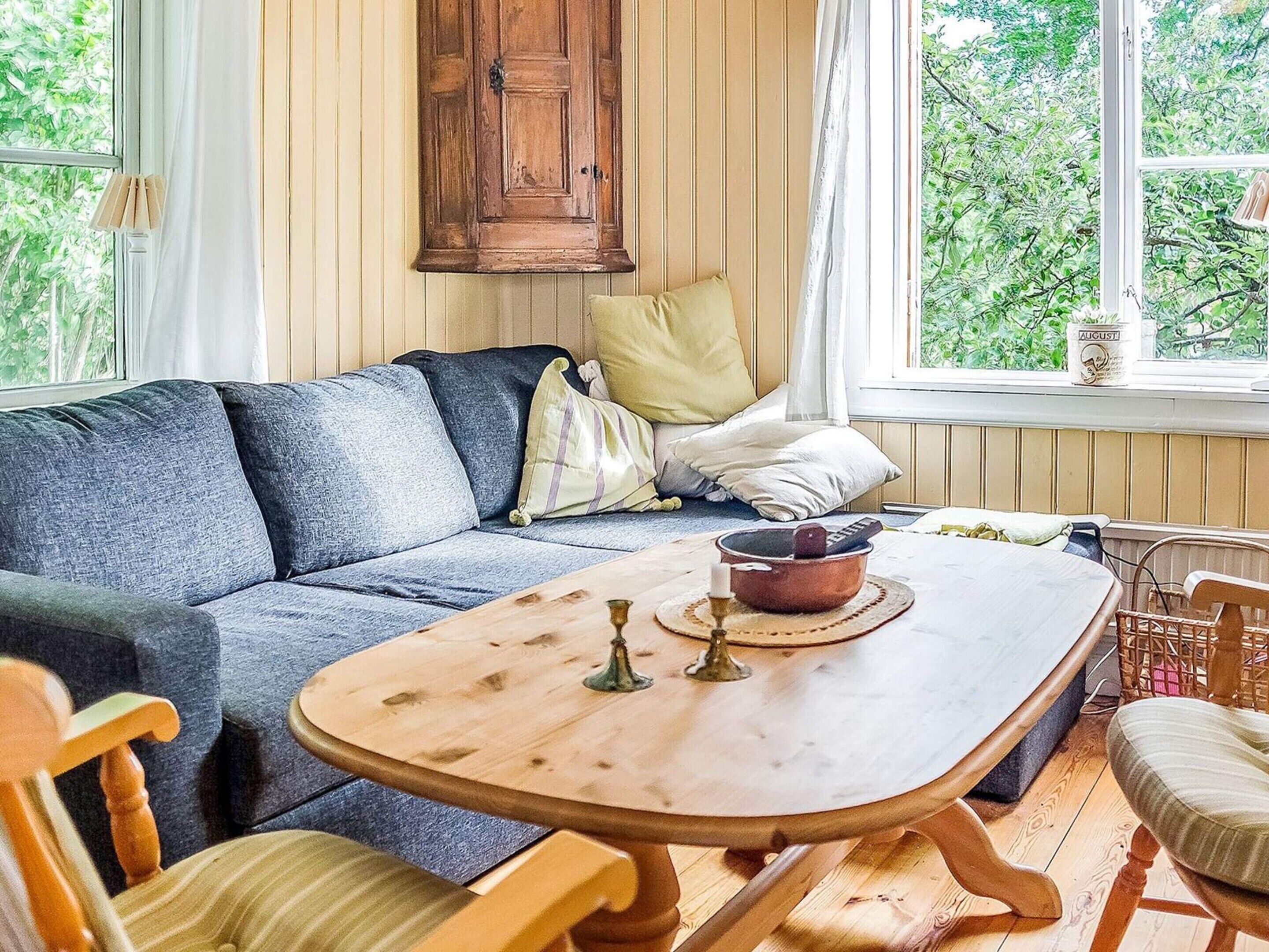 A cozy living room with a sofa, a wooden coffee table, and a view of greenery outside.