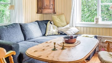 A cozy living room with a sofa, a wooden coffee table, and a view of greenery outside.