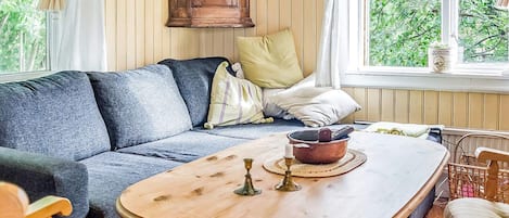 A cozy living room with a sofa, a wooden coffee table, and a view of greenery outside.