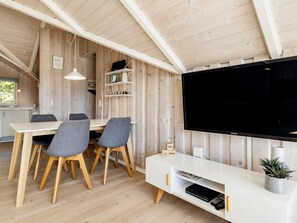 A modern interior with a dining area, a flat-screen TV, and a shelf with decorative items. - 6 Person Holiday Home in Vaeggerlose (Vaeggerlose)