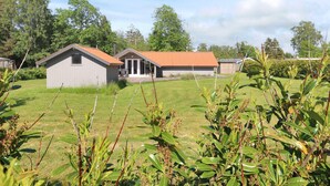 A rural property with two main buildings, one with a red roof and another with a grey roof, surrounded by a grassy field and trees. - 6 Person Holiday Home in Vaeggerlose (Vaeggerlose)