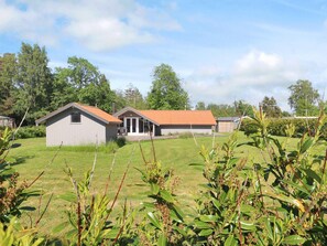 A rural property with two main buildings, one with a red roof and another with a grey roof, surrounded by a grassy field and trees. - 6 Person Holiday Home in Vaeggerlose (Vaeggerlose)