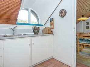 Une cuisine avec une fenêtre, un évier et une planche à découper en bois.