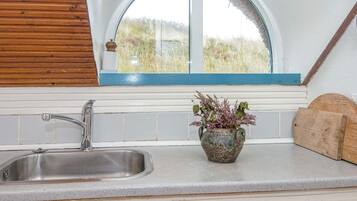 A kitchen with a window, a sink, and a wooden cutting board.