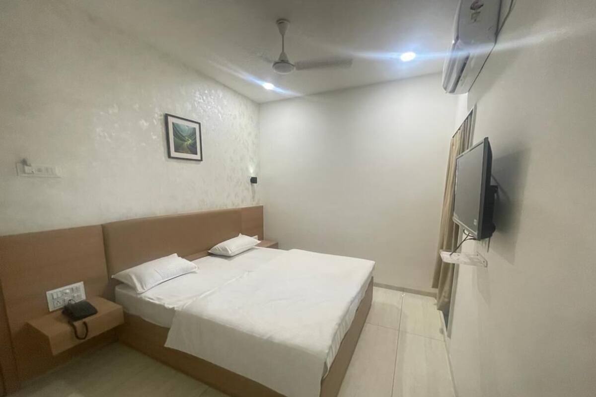 A bedroom with a bed, bedside table, and a TV mounted on the wall.