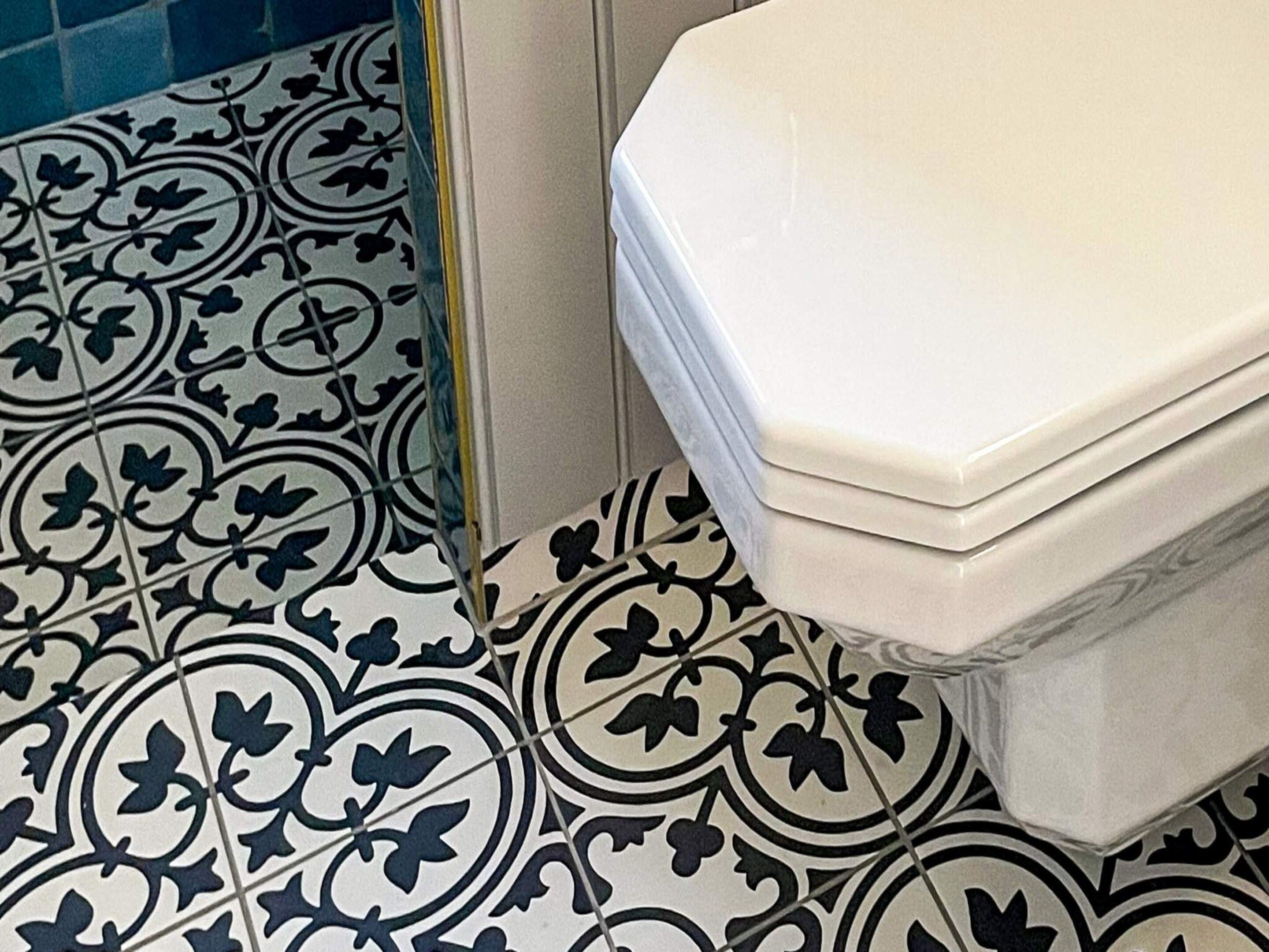 A bathroom with a white toilet and patterned floor tiles.