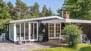 A house with a covered patio, a chimney, and a garden. - 4 Person Holiday Home in Vaeggerlose (Vaeggerlose)