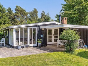 A house with a covered patio, a chimney, and a garden. - 4 Person Holiday Home in Vaeggerlose (Vaeggerlose)