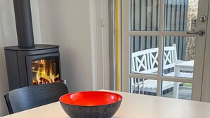 A modern interior with a black wood-burning stove, a white table, and a red bowl. - 4 Person Holiday Home in Vaeggerlose (Vaeggerlose)
