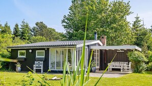 A small house with a porch, a chimney, and a garden. - 4 Person Holiday Home in Vaeggerlose (Vaeggerlose)
