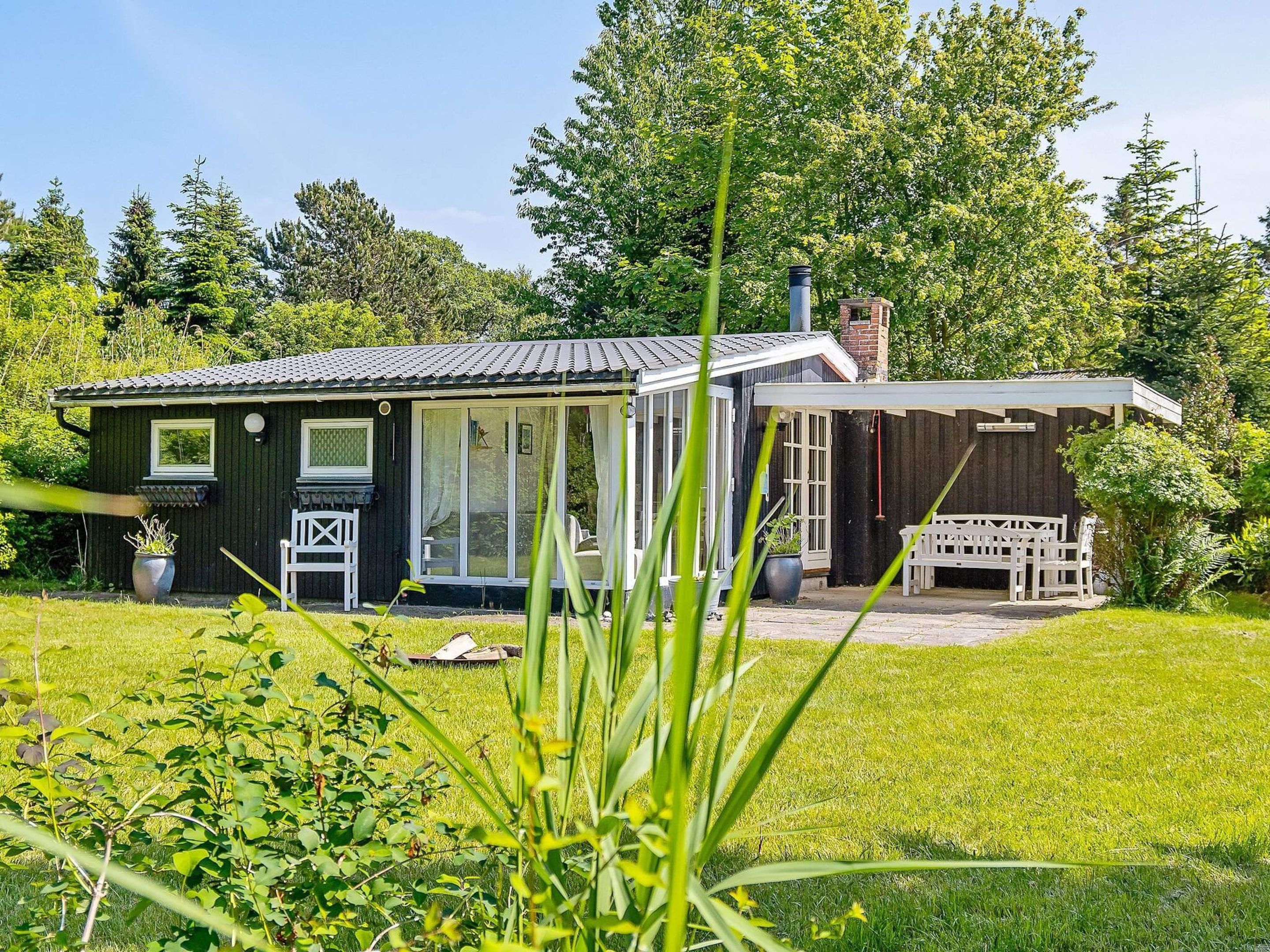 A house with a large glass door, a wooden deck, and a garden.