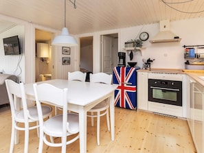 A compact kitchen with a white table and chairs, a coffee machine, and a clock on the wall. - 4 Person Holiday Home in Vaeggerlose (Vaeggerlose)