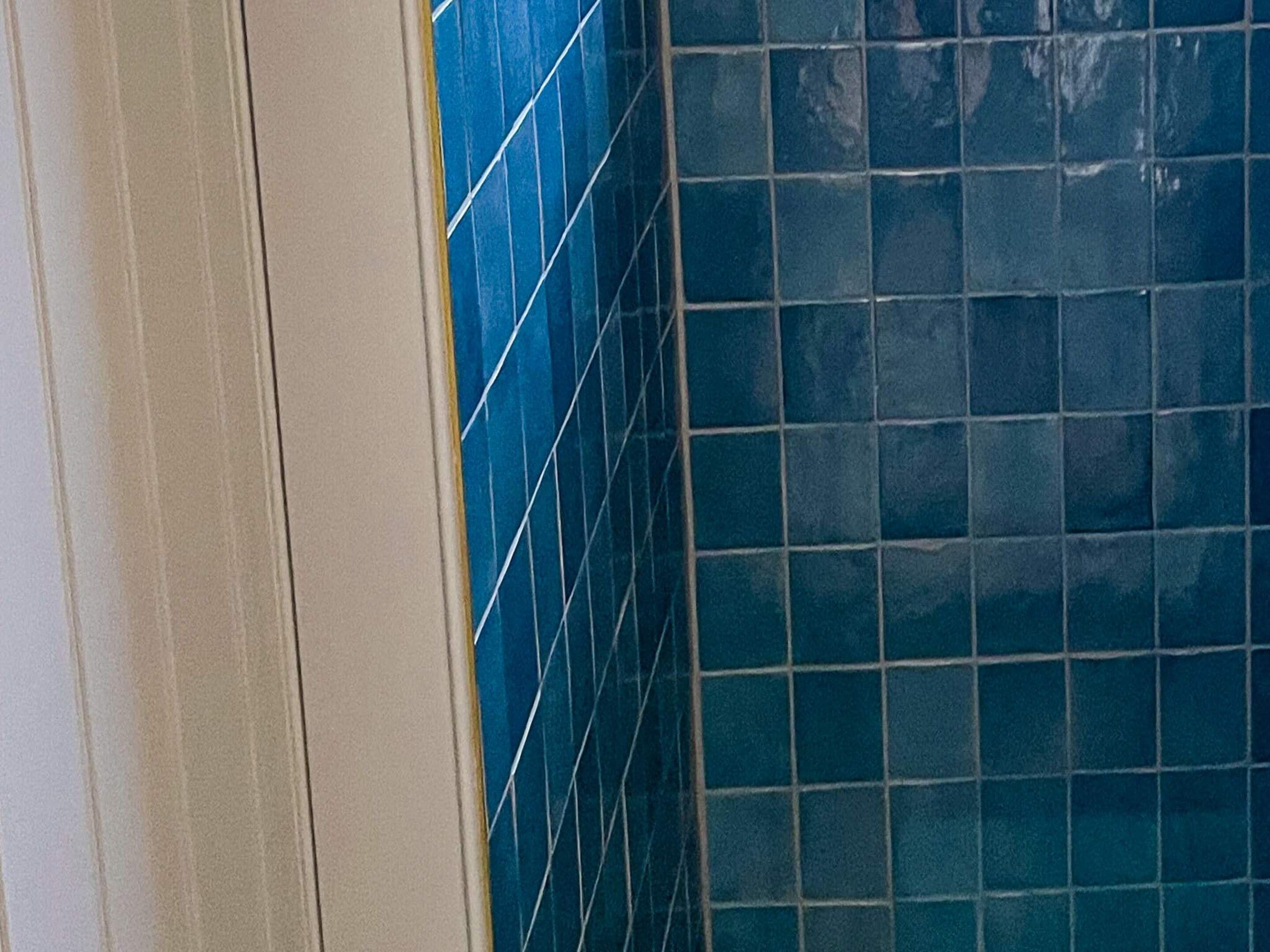 Een hoek van een kamer met blauwe betegelde wanden en een witte plint.