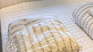 A bed with a quilted white mattress and two pillows with a floral pattern. - 4 Person Holiday Home in Vaeggerlose (Vaeggerlose)